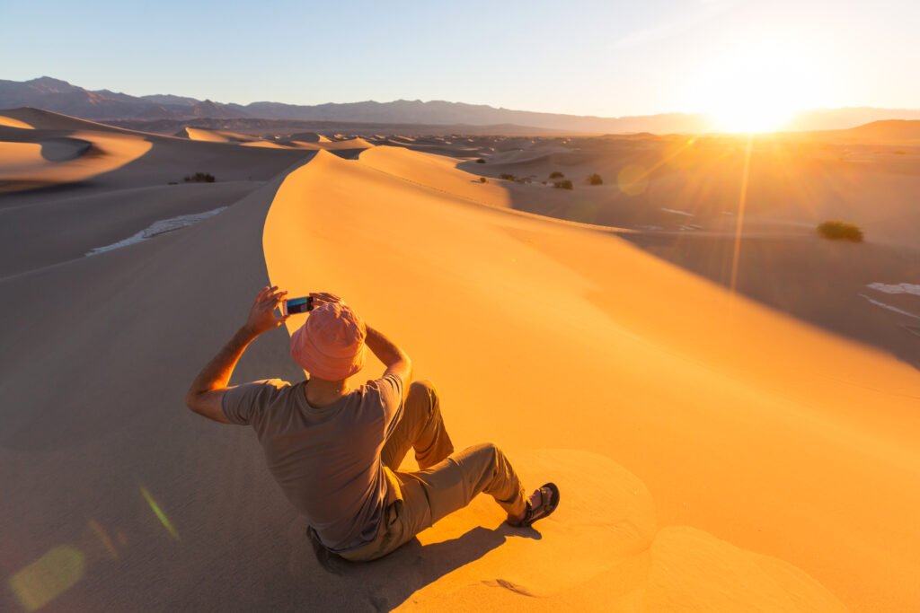 Hiker in sand desert. Sunrise time.