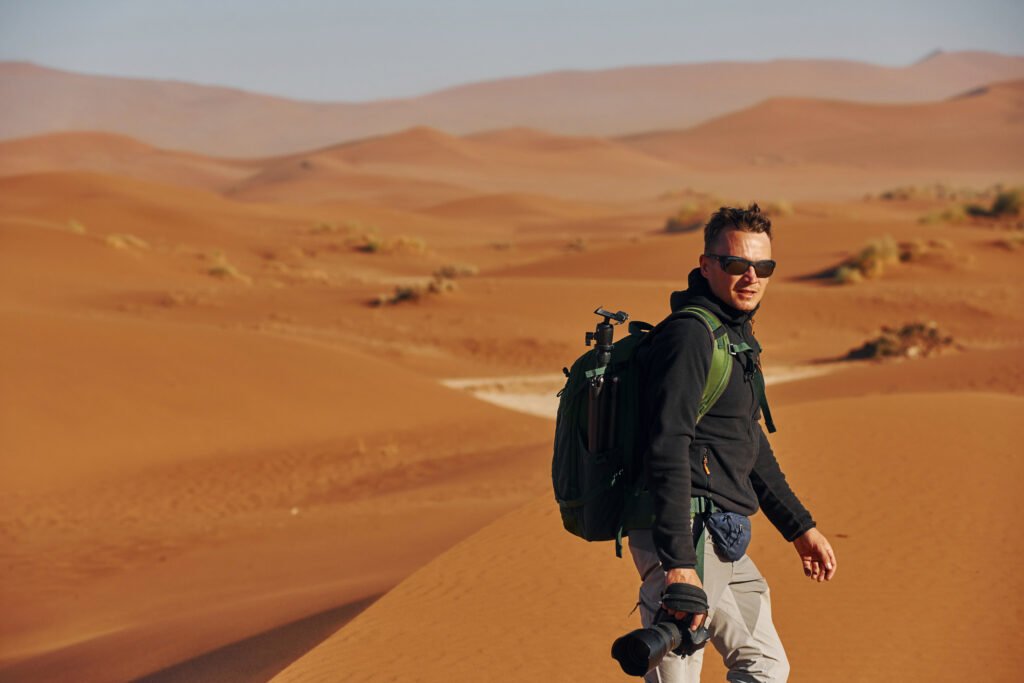 Photographer is working. Male tourist in casual clothes is in the deserts of Africa, Namibia.